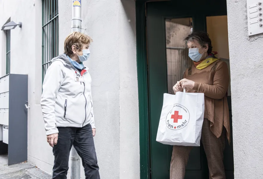 Freiwillige des SRK übergibt eine Einkauftstasche mit Grundnahrungsmitteln
